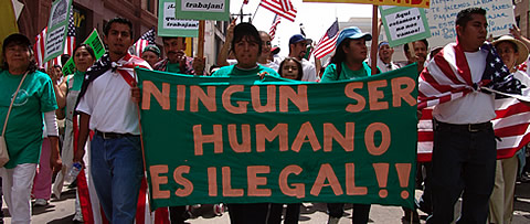 Immigrant activists hold sign reading Ningun Ser Humano Es Ilegal